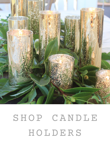 Image of gold glass candle holders with green foliage on table